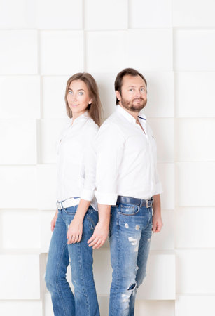 Portrait of a man and woman. Portrait of husband and wife in shirts against a white wall.の写真素材