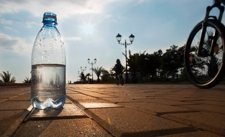 Bottle of water at sunset. The bottle stands on the waterfront.の写真素材