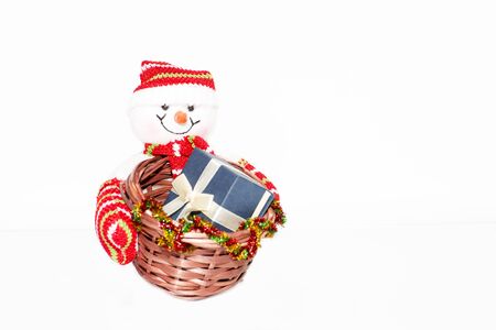 Snowman holding a basket with a gift box. Snowman toy on a white background.の写真素材