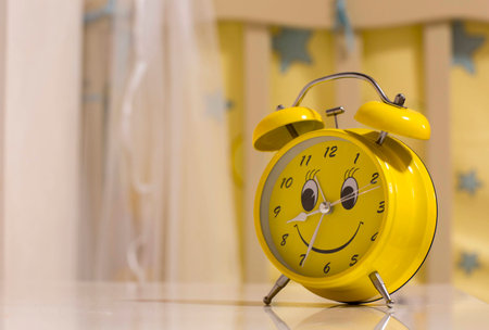 Yellow alarm clock with a smile. Table clock with eyes and a mouth.の写真素材
