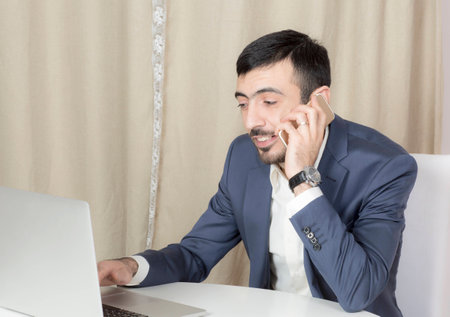 Portrait of a man with a laptop. A man sits at a Desk and working.の写真素材