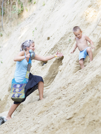 Ozora, Hungary - August 4, 2015: Ozora Festival, one of the greatest music gathering in Europe. Music festival in Hungary. Woman helps the child descend down the sandy slope.のeditorial素材