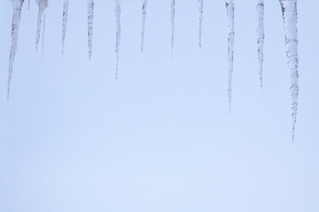 Icicles hanging from the roof of the house in winter.