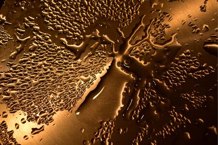 Drops of water on a yellow metal.