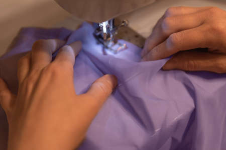 closeup portrait of young woman seamstress sitting and sews on sewing machine. Dressmaker work on...