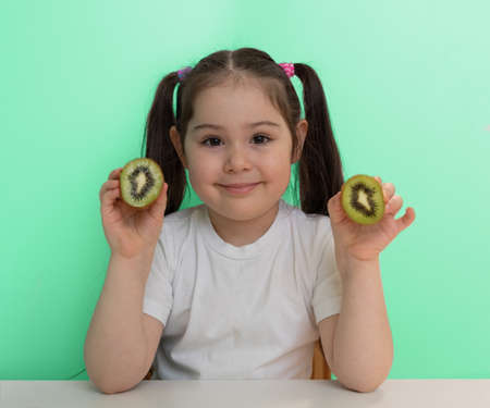 a little girl with a kiwi in her handsの写真素材