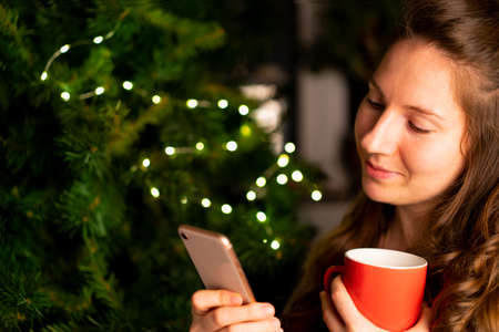 Christmas greetings online. a young girl uses a mobile phone to make a remote Christmas call to her...