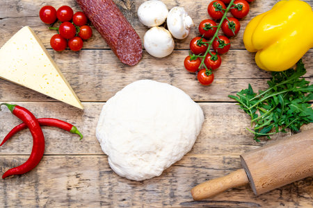 ingredients for making pizza and raw pizza before baking, on a wooden table, top view. High quality photoの写真素材
