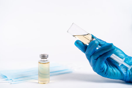 vaccine and medical masks on a white background, the doctors hands type the vaccine into the...