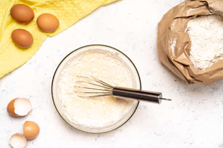 the process of making dough for pancakes with ingredients on a light table, eggs and flour are...