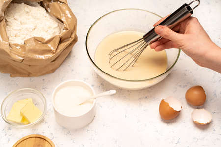 the process of making dough for pancakes with ingredients on a light table, eggs and flour are...