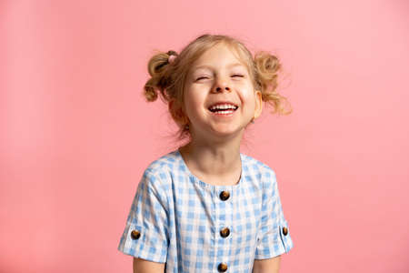 a little blonde girl on a pink isolated background with a cute smile.の写真素材