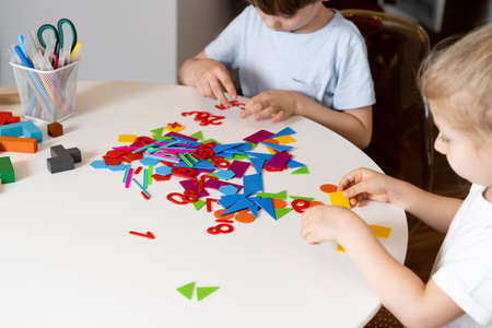a girl at a round white table plays educational games, a house made of designer children's hands, the concept of development of preschoolers.の写真素材