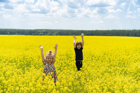 little girl and little boy in rapeseed field, brother and sister in flower field in summer.