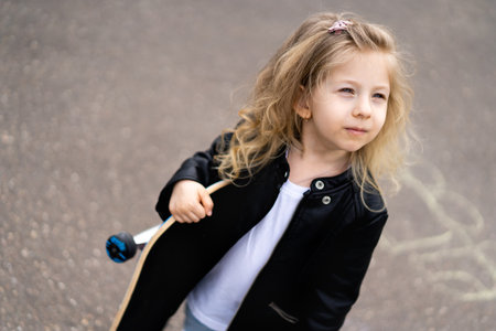 Little blonde girl on a skateboard in the city.の写真素材