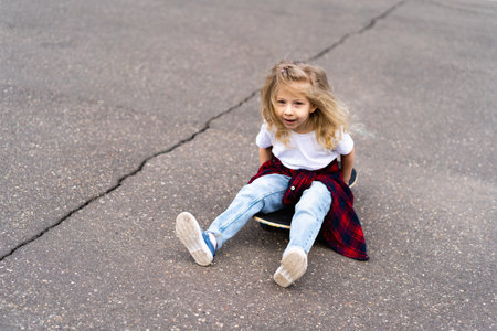 Little blonde girl on a skateboard in the city.の写真素材