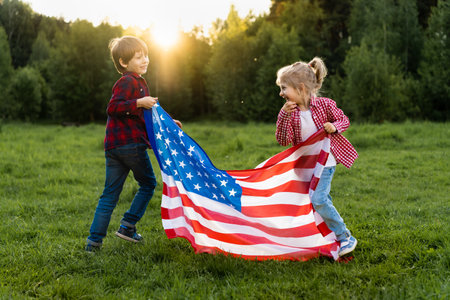 brother and sister with the American flag in the sunlight, happy children in the USA Independence Dayの写真素材