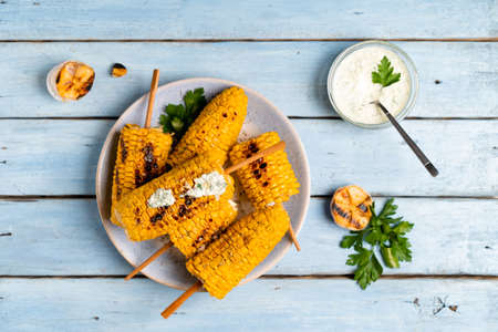 fried corn on a light plate and a blue wooden table with sauce, top viewの写真素材