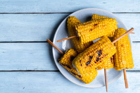 fried corn on a light plate and a blue wooden table, top view, copy spaceの写真素材