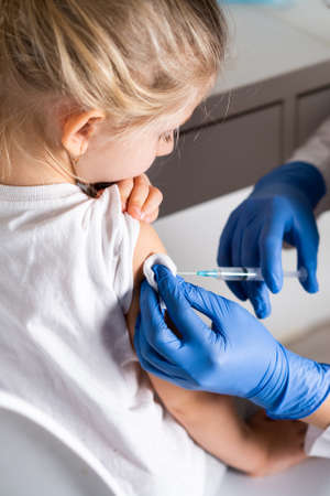 vaccination of children, a little girl at a doctors appointment, an injection in the arm.の写真素材