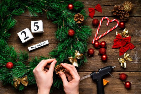 making and decorating a Christmas wreath with your own hands on a wooden background, handmade decor for the New Yearの写真素材