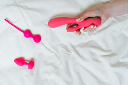 light background with different sex toys. a vibrator in a womans hands. Stay-at-home concept, place for textの写真素材