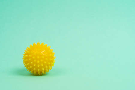 yellow ball of a massage needle on a turquoise background, the concept of prevention of flat feet,...