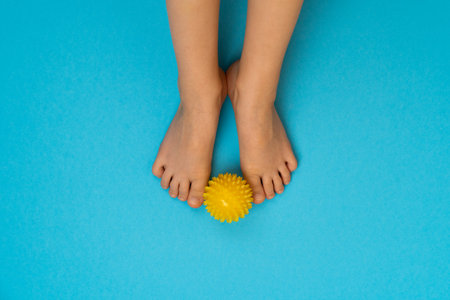 yellow needle ball for massage and physiotherapy on a blue background with the image of childrens feet, the concept of prevention and treatment of hallux valgusの写真素材