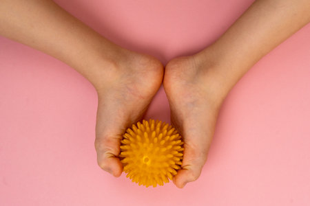 yellow needle ball for massage and physical therapy on a pink background with a childs foot, the...