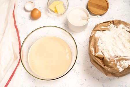 the process of making dough for pancakes with ingredients on a light table, eggs and flour are whipped with a mixerの写真素材