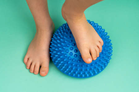 childrens feet with a blue balancer on a light green background, treatment and prevention of flat...