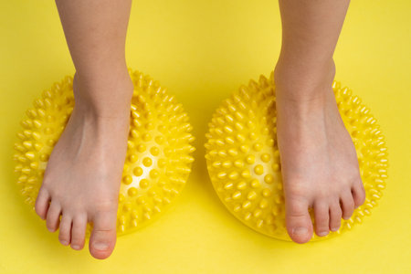children's feet with a yellow balancer on a light yellow background, treatment and prevention of flat feet, valgus deformity of the foot.の写真素材