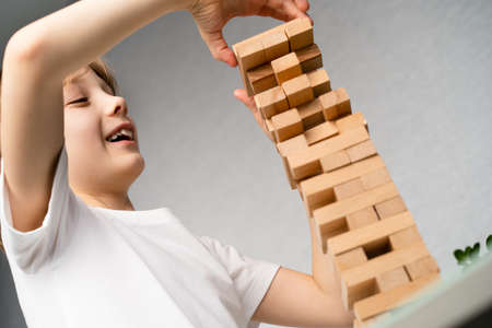 happy boy playing board game, building a tower of wooden cubes, jenga logic game for child...