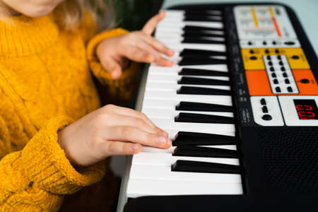 a little girl playing the synthesizer, the concept of teaching children music, hands close-upの写真素材