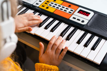 a little girl playing the synthesizer, the concept of teaching children music, hands close-upの写真素材