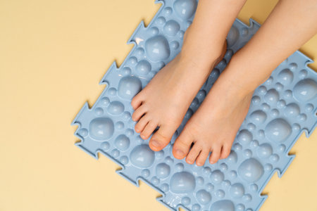 childrens feet on a blue orthopedic rug on a beige background, treatment and prevention of flat feet, hallux valgusの写真素材