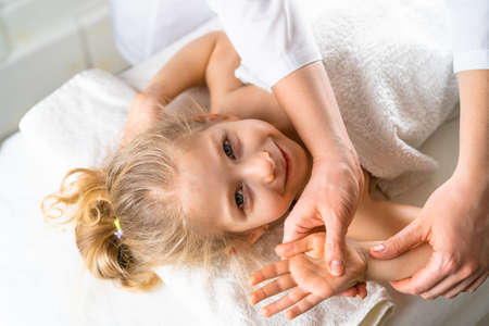 a woman gives a massage to a little girl, childrens massage, prevention of scoliosis, osteopathyの写真素材