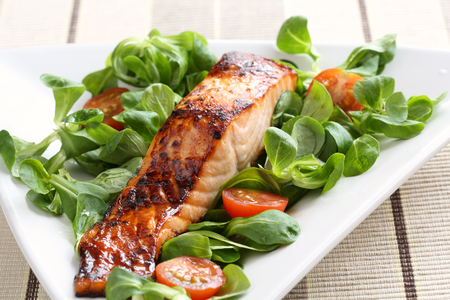 Grilled salmon with a honey glaze on a bed of lambs lettuceの写真素材