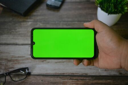 Self Perspective smartphone In the hands of a man with green screen for key chroma screen.の写真素材