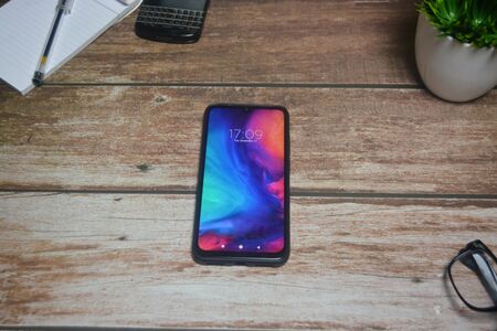 Smartphone with flower in a vase on wood tableの写真素材
