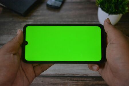Self Perspective smartphone In the hands of a man with green screen for key chroma screen.の写真素材