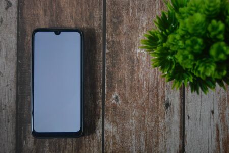 Smartphone with flower in a vase on wood tableの写真素材