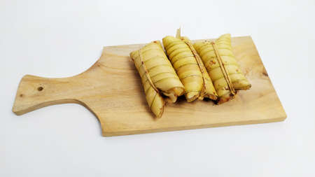 Lepet or leupeut Indonesian traditional food with glutinous rive and grated coconut ingredients wrapped in coconut leaves isolated on white backgroundの写真素材