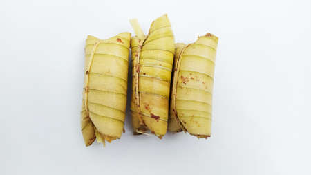 Lepet or leupeut Indonesian traditional food with glutinous rive and grated coconut ingredients wrapped in coconut leaves isolated on white backgroundの写真素材