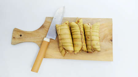 Lepet or leupeut Indonesian traditional food with glutinous rive and grated coconut ingredients wrapped in coconut leaves isolated on white backgroundの写真素材