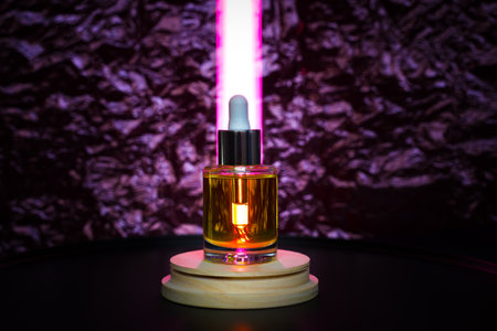Face oil on a wooden podium with tube light behind lighting the dropper. Front viewの写真素材