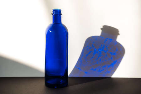 Dark blue glass bottle on white and black background. Side viewの写真素材