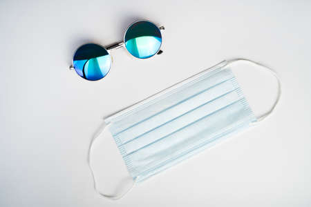 Blue Sunglasses and a non reusable blue face mask on a white background. Summer and conceptの写真素材