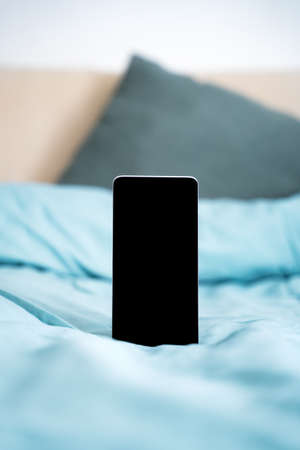 Blank vertical phone on blue bed background with pillows. Sleeping meditation app mockupの写真素材