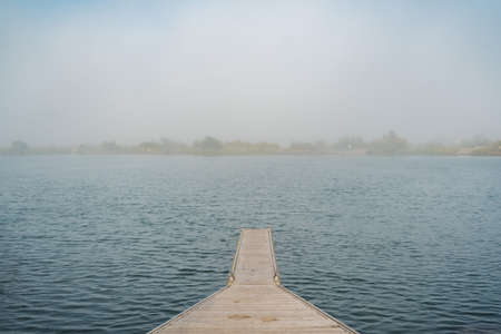 Pier on a lake with misty shores